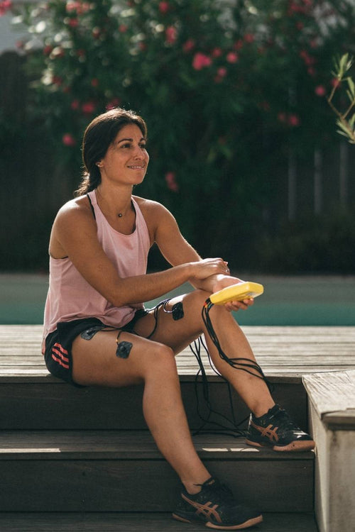 A woman relaxing after doing a quad muscle strengthening session with the Compex Fitness EMS muscle stimulator