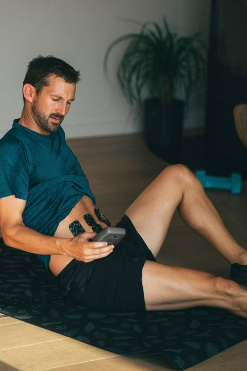 A man doing ab crunches, using the Compex Sport Elite EMS muscle stimulator to strengthen his ab muscles