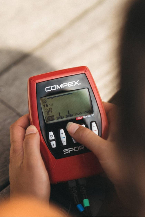 A woman using the Compex Sport EMS muscle stimulator for a pain relief session