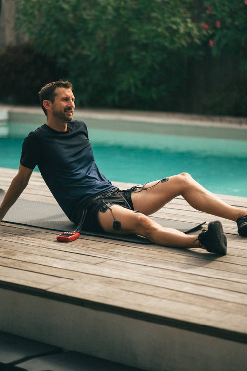 A man using the Compex Sport EMS muscle stimulator for a quad muscle recovery session