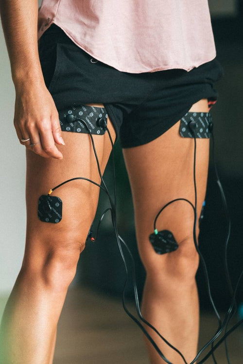 A woman doing a quad muscle strengthening session, using the Compex 6P Snap Cables