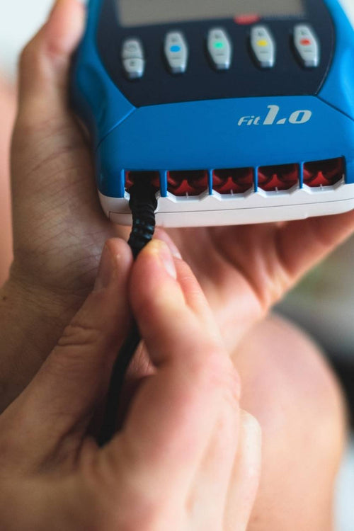 A person putting the Compex FIT 1.0 EMS muscle stimulator on charge