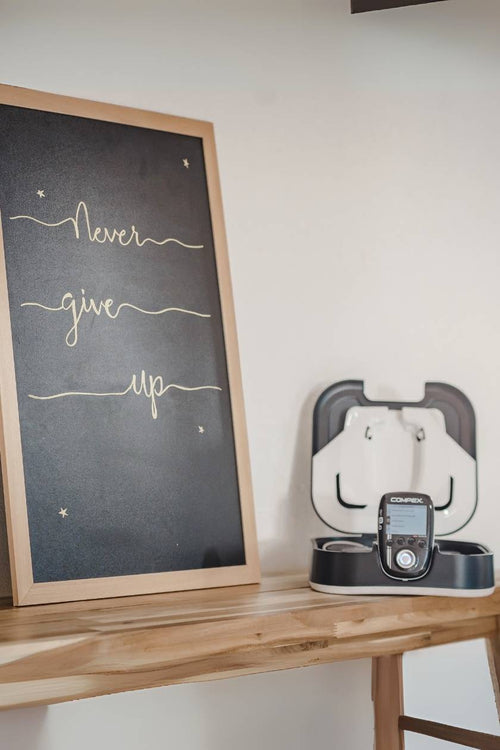 The Compex SP 8.0 EMS muscle stimulator charging in its docking station