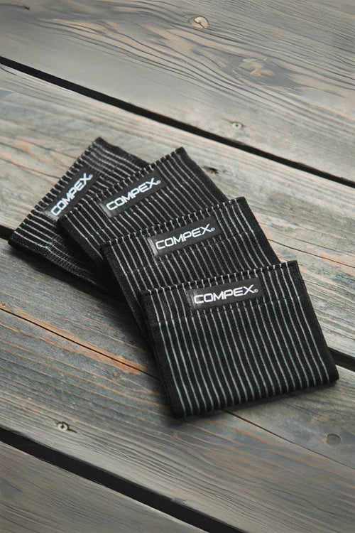 The Compex Elastic Straps (x4) on a wooden bench