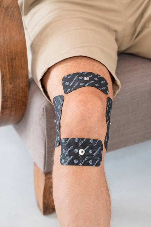 A man with four large 1-snap Compex electrodes on his knee