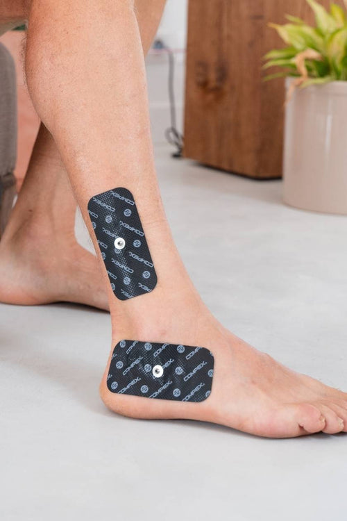A woman with large 1-snap Compex electrodes on her ankle