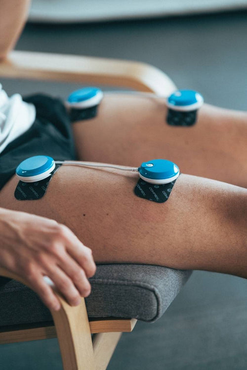 A woman doing a quad muscle recovery session, using the Compex FIT 5.0 EMS muscle stimulator