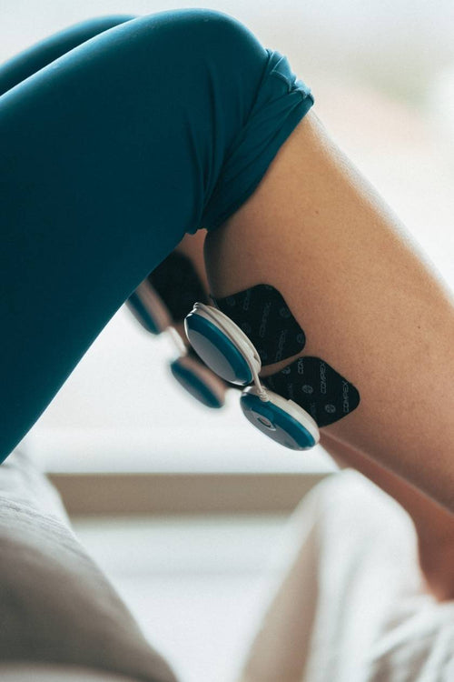 A woman doing a calf muscle recovery session, using the Compex FIT 5.0 EMS muscle stimulator