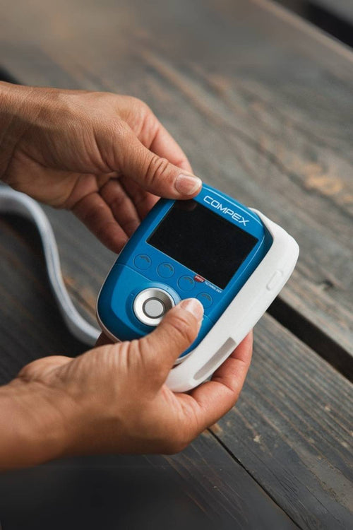 A person putting the Compex FIT 5.0 into the Compex Protective Case for Wireless EMS Muscle Stimulators with lanyard (white)