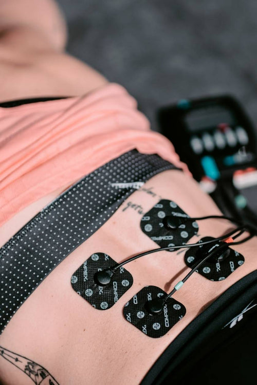 A woman using the Compex SP 2.0 for a core muscle strengthening session