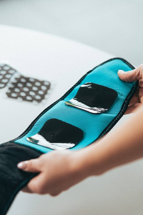 A woman holding the Compex Corebelt EMS muscle stimulator belt