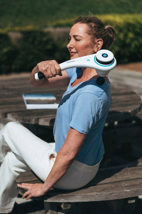 A woman using the Compex Fixx™ Mini massage gun for a shoulder massage