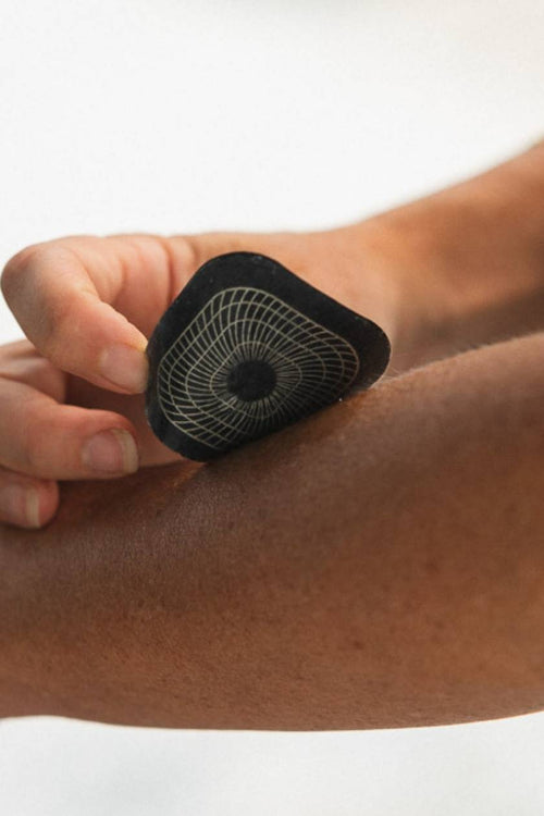 A person placing a Compex electrode on their skin