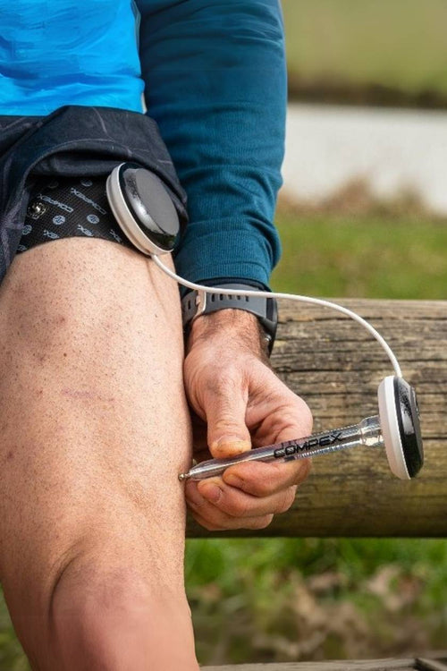 A man using the Compex Motor Point Pen to find the ideal electrode placement on his quad muscle