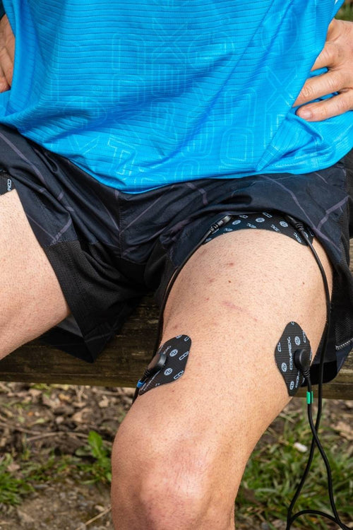 A man strengthening his quad muscles using a Compex EMS muscle stimulator