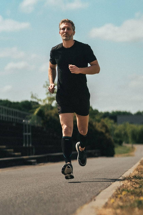 A man running on a path, wearing the Compex Activ'® Calf Support Sleeves