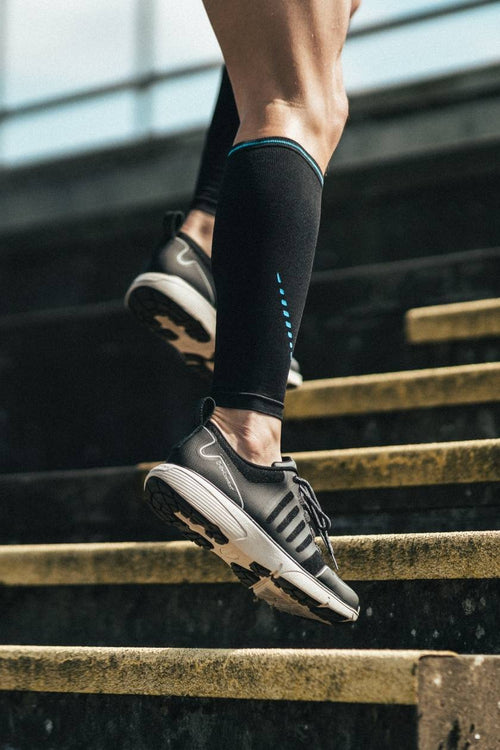 A man running up some stairs, wearing the Compex Activ'® Calf Support Sleeves