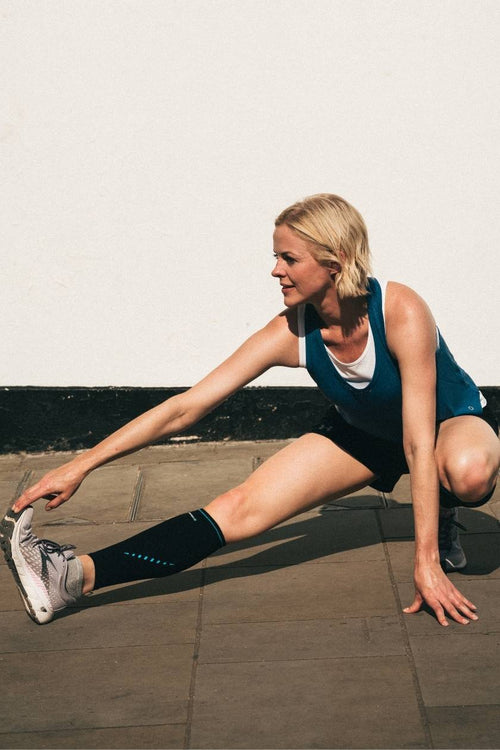 A woman stretching, wearing the Compex Activ'® Calf Support Sleeves
