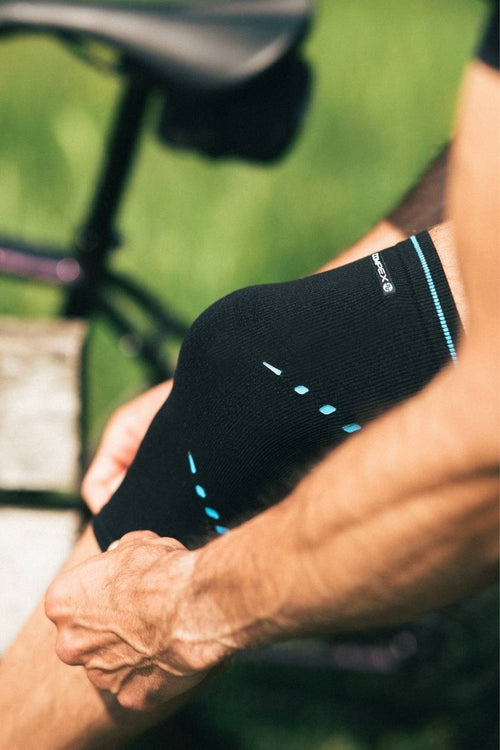 A cyclist putting on the Compex Activ’® Knee Support