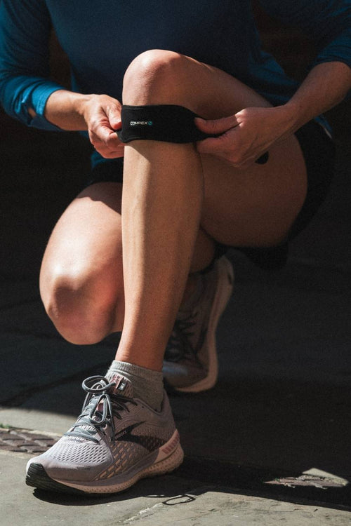A woman putting on the Compex Activ'® Patella support strap