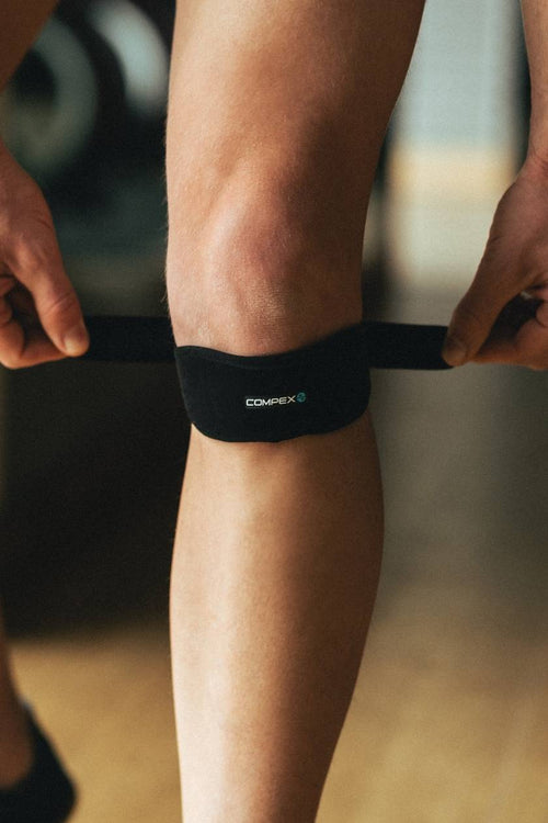 A man putting on the Compex Activ'® Patella support strap