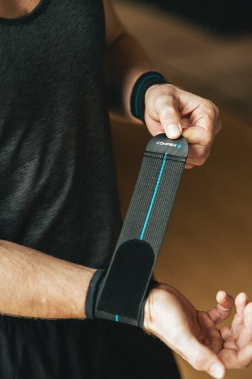 A man putting on the Compex Activ'® Wrist Band+ Support