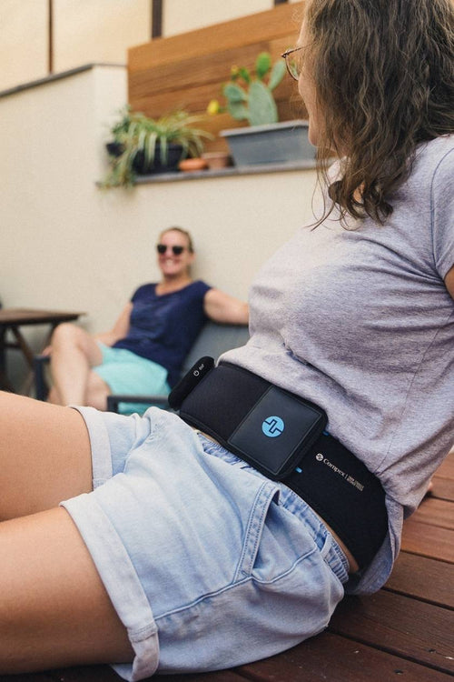 A woman using the Compex ComfortTENS Back Wrap