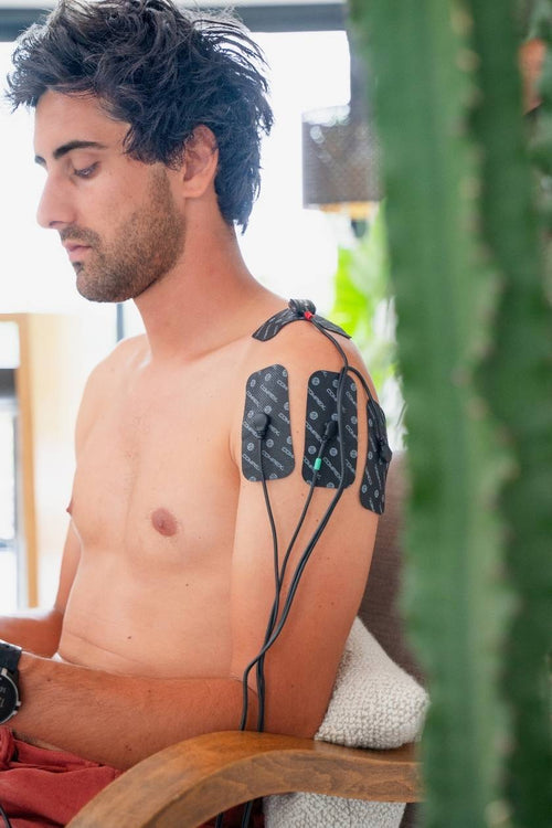 A man using the Compex FIT 3.0 EMS muscle stimulator for a shoulder pain relief session