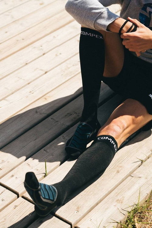 A woman sitting outside wearing the Compex Recovery Socks