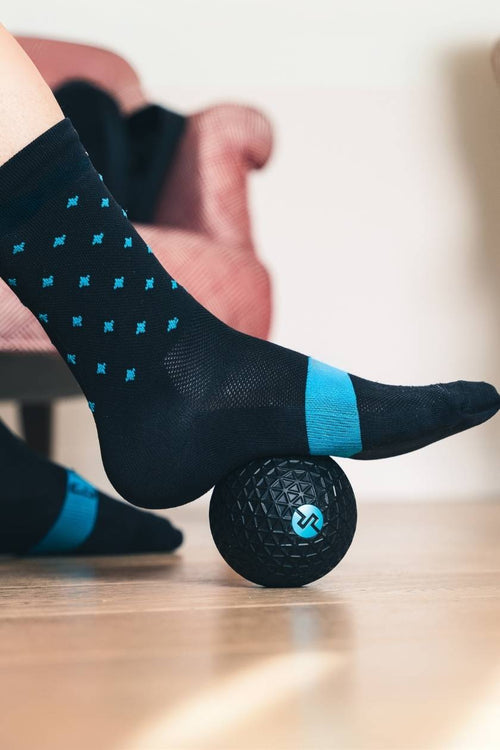 A woman rolling her foot on the Compex Molecule vibrating massage ball