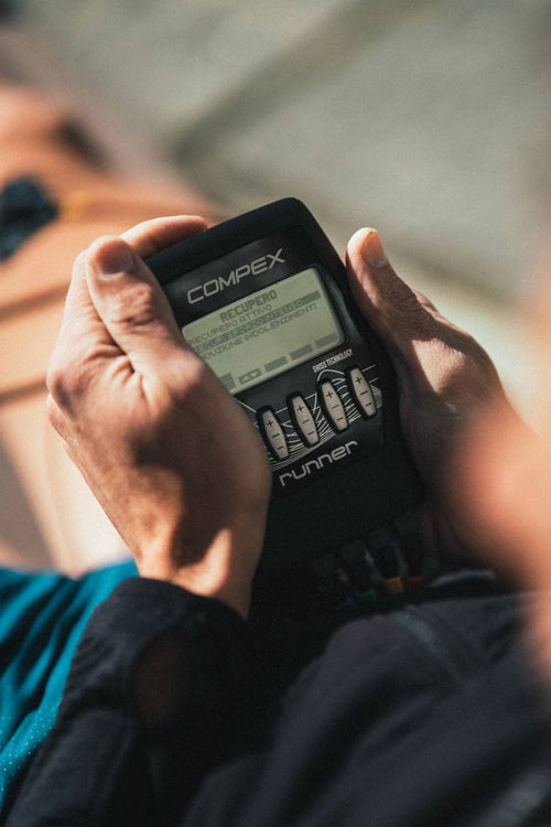 A man using the Compex Runner EMS muscle stimulator for a recovery session
