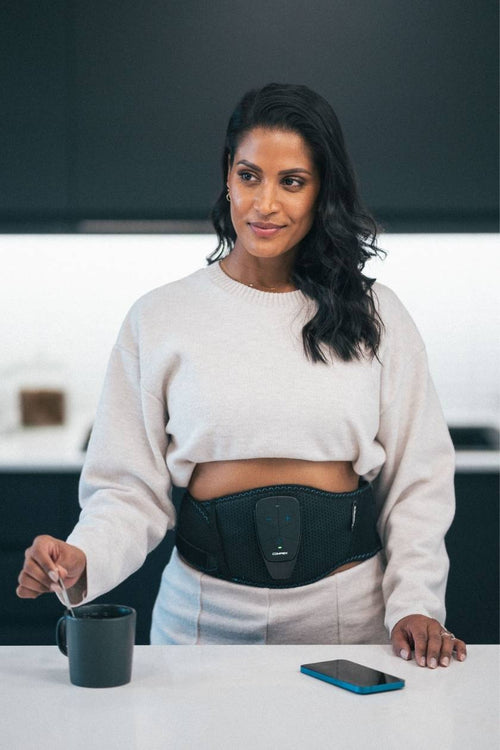 A woman using the Compex Corebelt EMS muscle stimulator belt to tone her arms