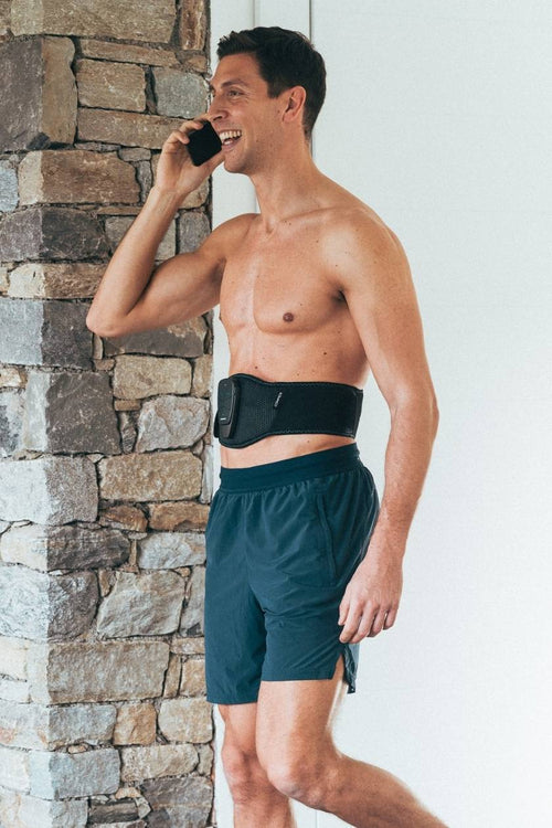 A man using the Compex Corebelt EMS muscle stimulator belt to tone his abs