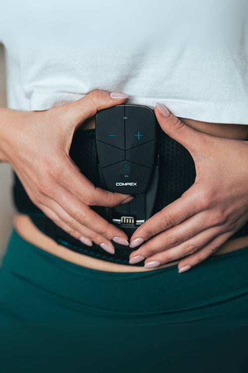 A woman putting the Compex Corebelt EMS muscle stimulator unit in the belt
