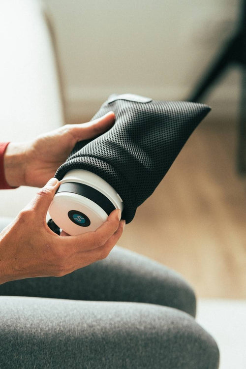 A woman take the Compex Fixx™ Mini massage gun out of it's duffle bag