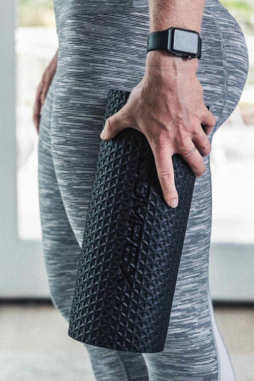 A woman holding the Compex Ion™ vibrating massage roller