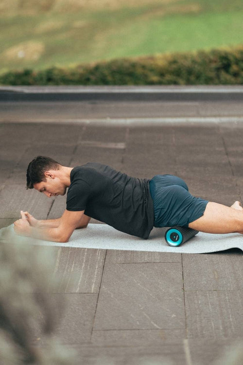 A man massaging his quad muscle using the Compex Ion™ vibrating massage roller