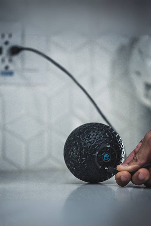 A man plugging in the Compex Molecule™ vibrating massage ball to charge it