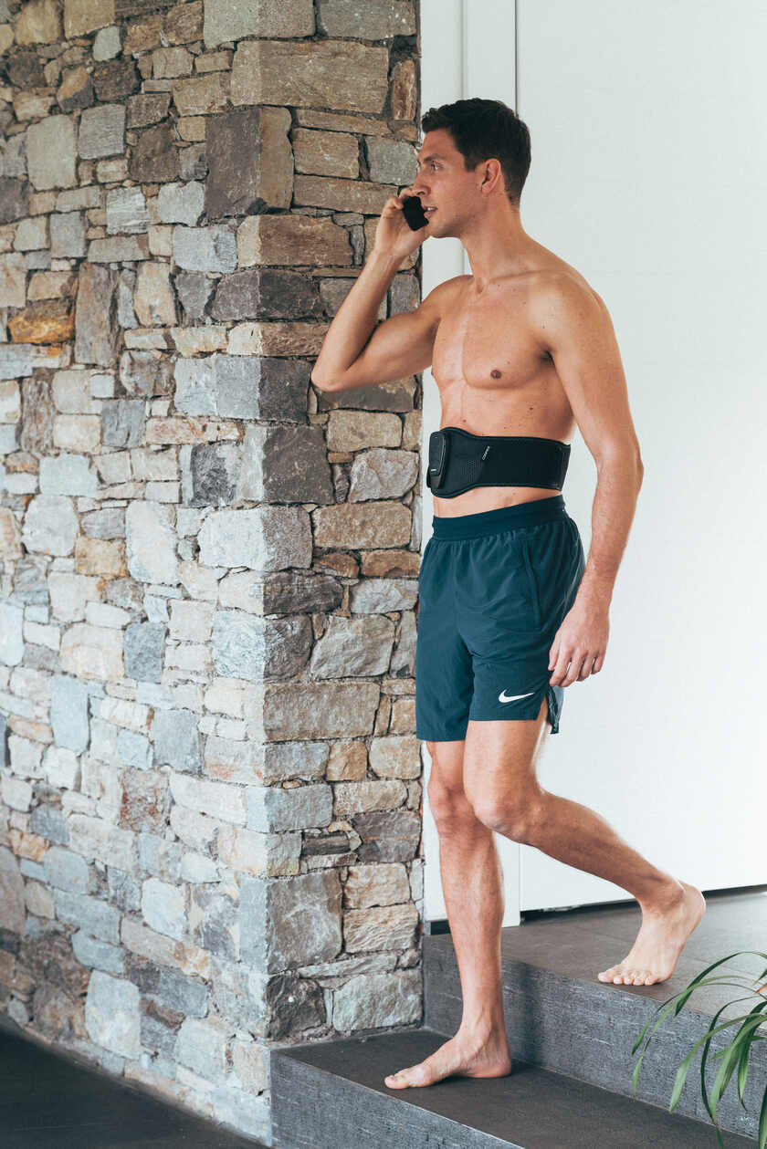 A man using the Compex Corebelt EMS muscle stimulator belt