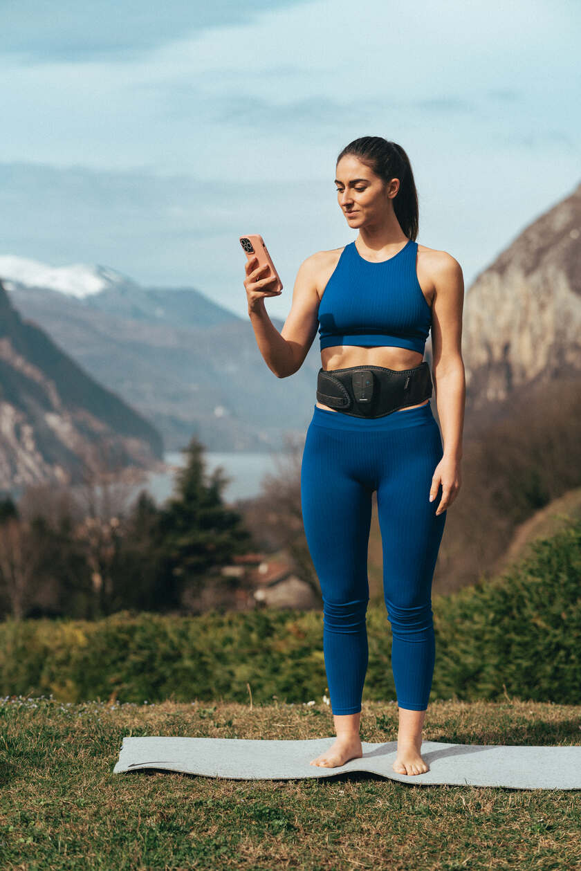 A woman using the Compex Corebelt EMS muscle stimulator belt