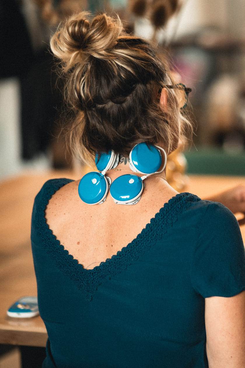 A woman using the Compex FIT 5.0 EMS muscle stimulator to relieve neck pain