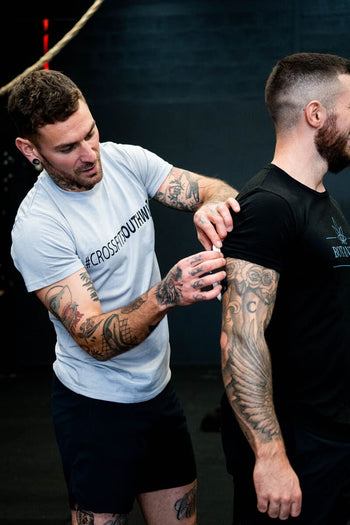 A man instructing another man on how to use his electrical muscle stimulation (EMS) device
