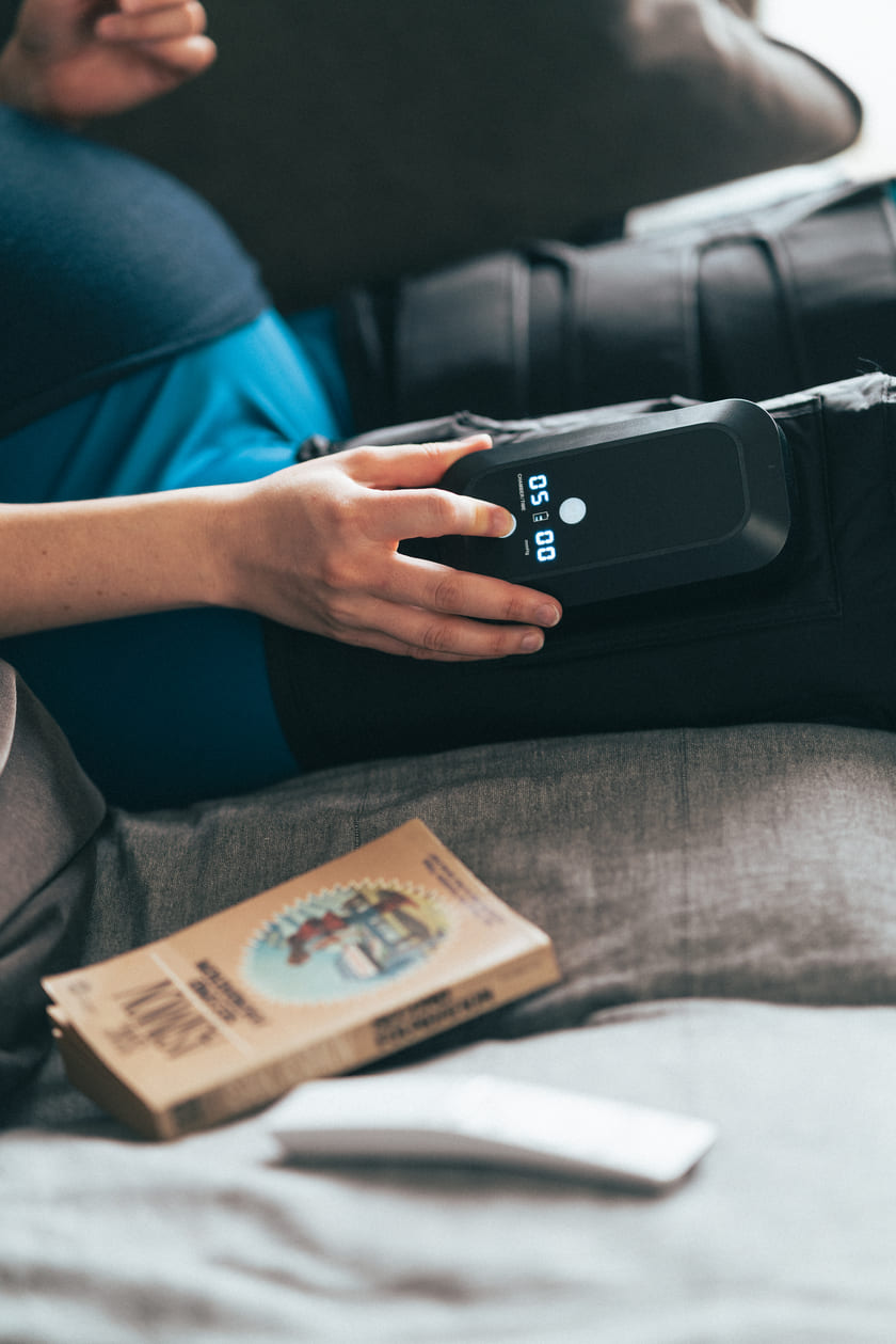 A woman adjusting the settings on the Compex Ayre™ compression boots