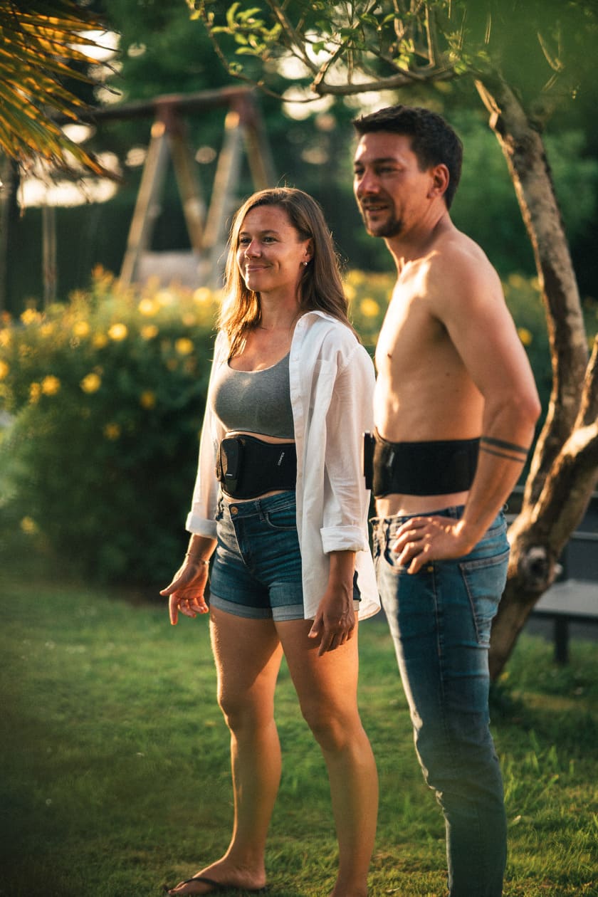 A man and a woman using the Compex Corebelt EMS muscle stimulator belt together