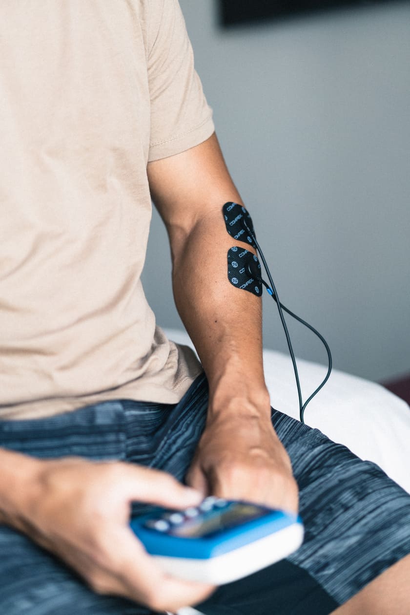 A man treating tight forearms muscles using the Compex FIT 3.0 EMS muscle stimulator