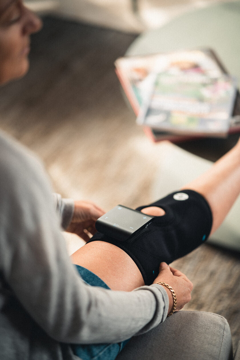 A woman using the Compex ComfortTENS Knee wrap
