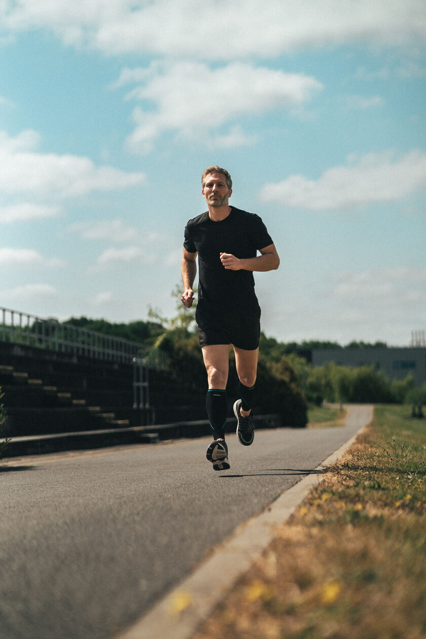 A man running while wearing the Compex Activ' calf sleeves