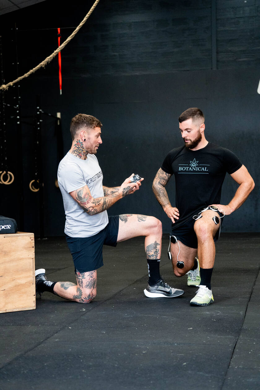 A man being coached by another man, using the Compex SP 8.0 EMS muscle stimulator