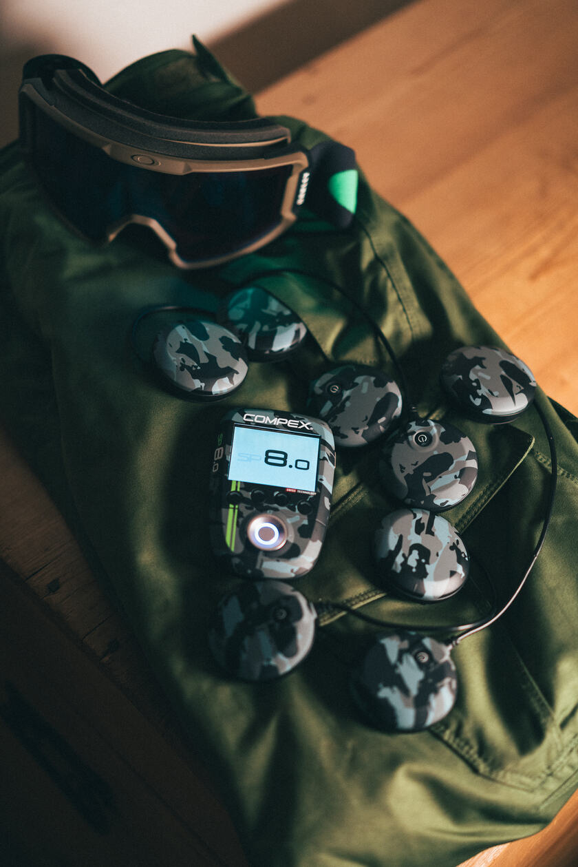 The Compex SP 8.0 WOD Edition on a bag with some skiing goggles