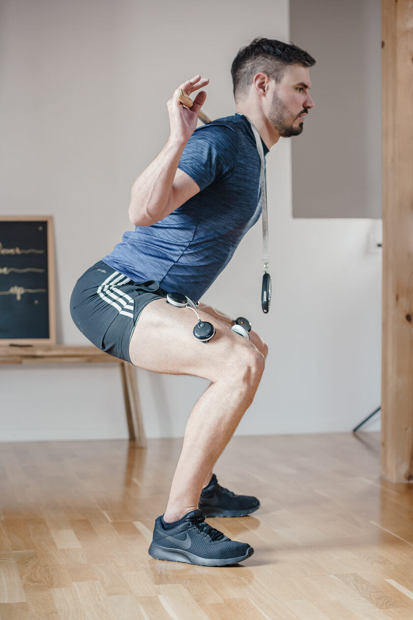 A man doing a squat using the Compex SP 8.0 EMS muscle stimulator